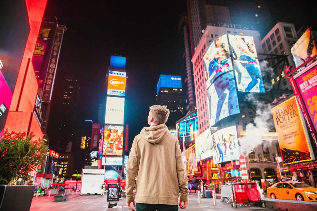 Jove mirando la publicidad digital en los edificios en times square